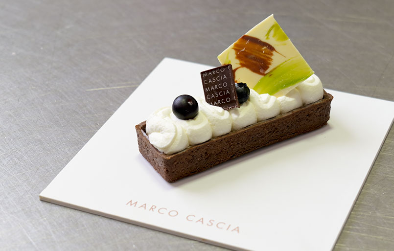 Per pasta frolla al cacao: setacciare le polveri (farina, cacao amaro, zucchero a velo), aggiungere il burro Trevalli Professional ammorbidito tagliato a tocchetti, i semi di vaniglia e i tuorli. Formare un panetto, avvolgere con pellicola e far riposare in frigorifero per 30 minuti. Dopo il raffreddamento stendere la frolla a 3 mm, inserirla nello stampo, bucherellare il fondo e cuocere a 175 °C per 15 minuti. Sfornare e lasciare raffreddare.